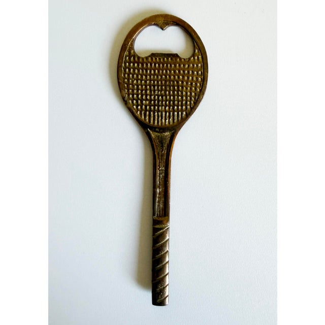 A charming and stylish 1970s tennis racket-shaped brass bottle opener. Perfect for gifting. Unmarked.