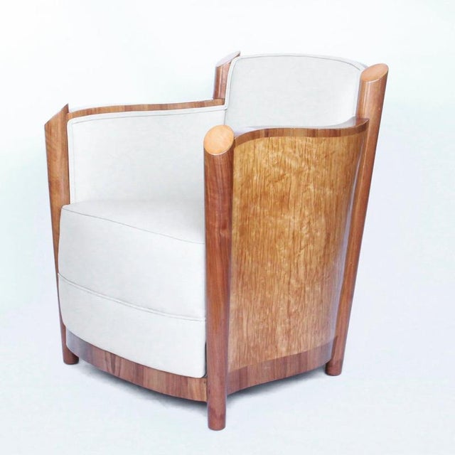 A pair of art deco club chairs by maurice adams. Walnut and birds-eye maple veneer. Upholstered in cream leather....