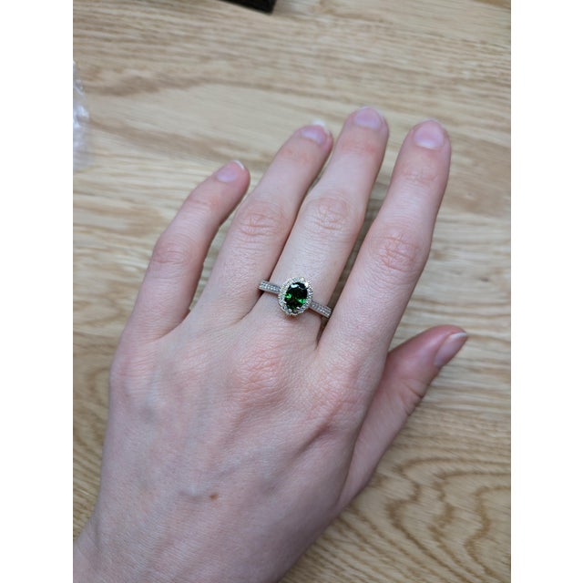 A vivid tsavorite gemstone takes center stage in this dual-tone 14K gold ring, framed by a sparkling halo of natural...