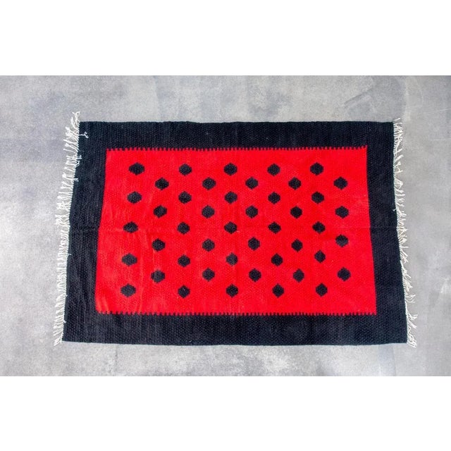 In this listing you will find a beautiful hand-woven kilim in red and black wool. It features geometrical pattern,...