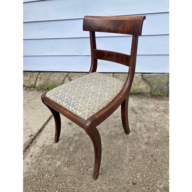 These are 19th-century mahogany dining side chairs in the Federal or Regency style, featuring a curved back rail and sabre...