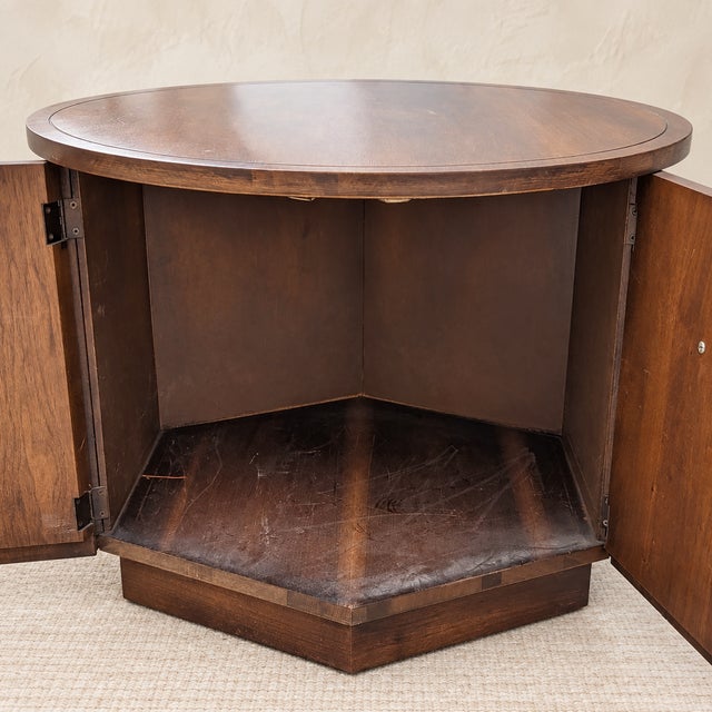 A sculptural round walnut cabinet table from the 1970s, combining a warm wood surface with concealed storage behind curved...