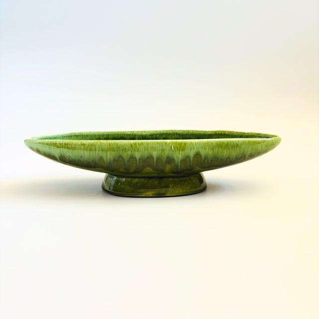 A mid century pottery bowl. Long oval shape on a pedestal base with a beautiful green drip glaze. Measures 14.25"W x 4.5"D...