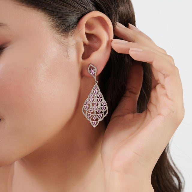 These pink sapphire and diamond dangle earrings feature an intricate openwork design crafted in 925 sterling silver. A...