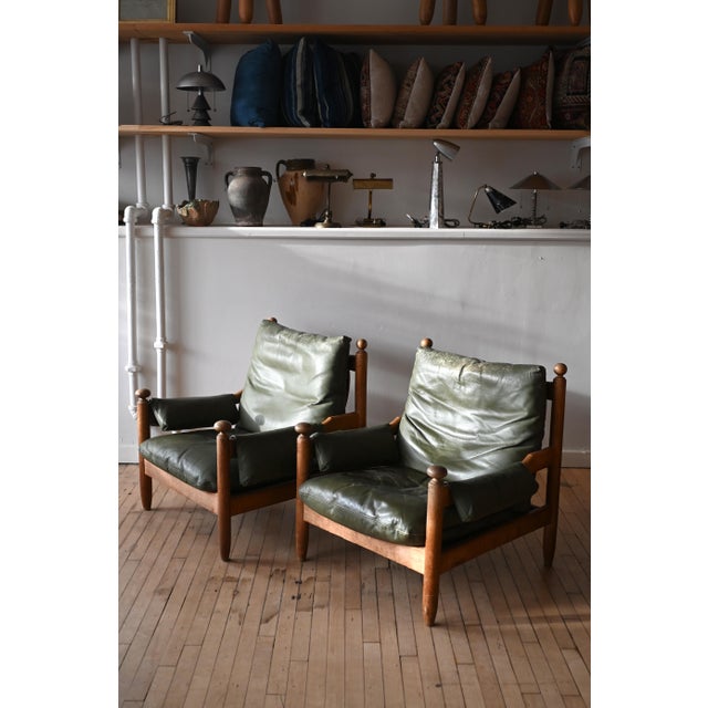 Gorgeous pair of French oak and leather lounge chairs styled after Eric Merthen's "Amiral" chair. Great patina on the...