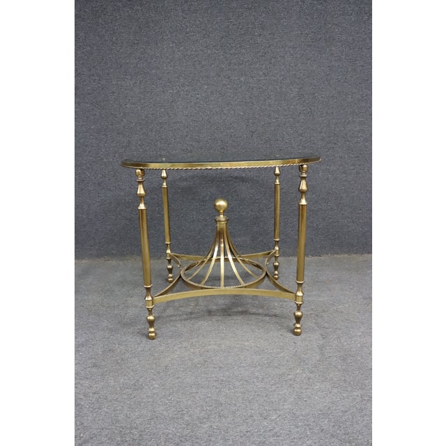 Elegant Italian solid brass center table featuring a round beveled glass top, turned legs, and a sculptural pedestal base...