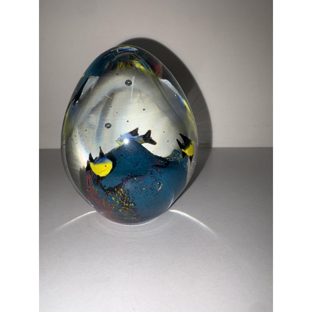 Egg-shaped art glass paperweight with small tropical fish submerged on a blue seabed, height 12 cm, circumference 7 cm