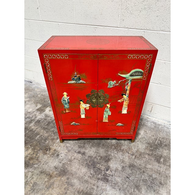 This is the perfect little cabinet for a small area. Bright Chinese red lacquer, with raised figural relief on the front...
