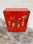 This is the perfect little cabinet for a small area. Bright Chinese red lacquer, with raised figural relief on the front...