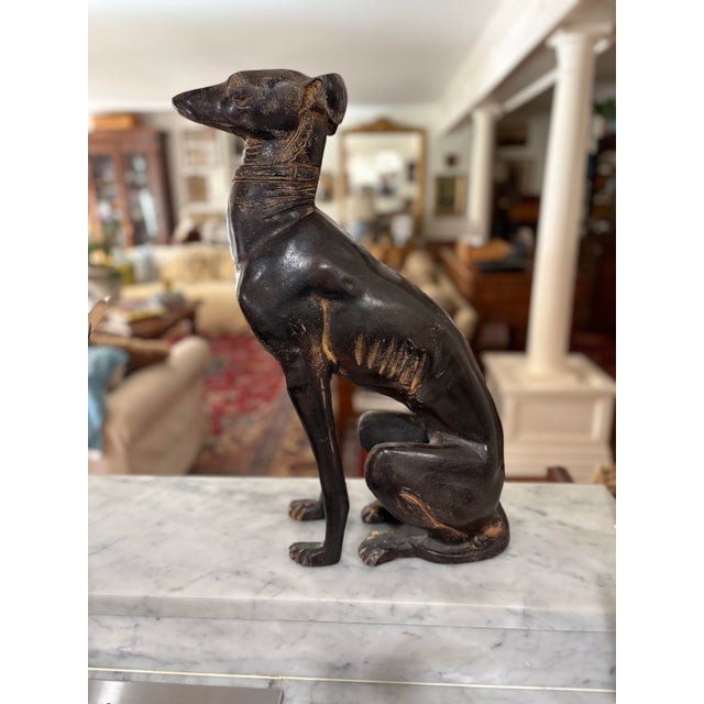 A striking blend of elegance and symbolism, this 21-inch cast metal dog statue captures the refined silhouette of a...