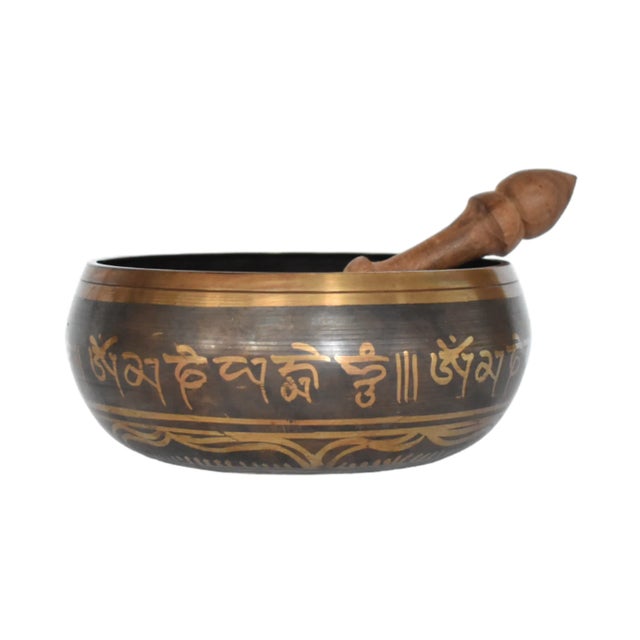 A Tibetan brass singing bowl with mantra writing on the outside and interior ornamental designs, with the five Dhyani...