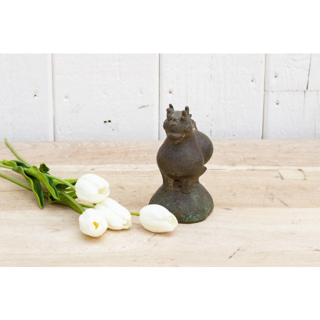 A rare solid bronze opium weight showcasing a mythical foo dog figure, geometric engraving and aged patinated finish. This...