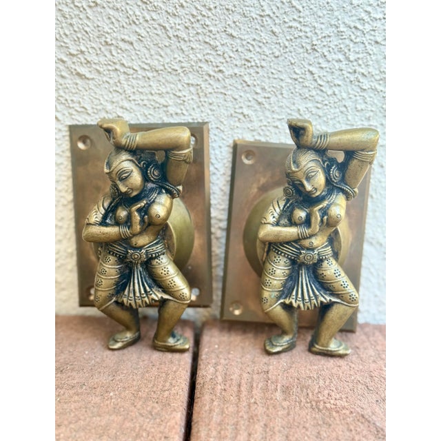 A striking pair of vintage solid brass door handles depicting graceful Indian temple dancers. Each sculpted figure...
