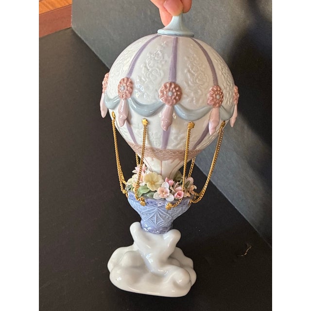 The basket of the hot air ballooon is filled with flowers.