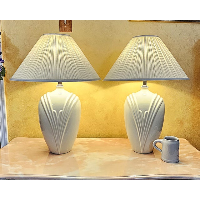 A beautifully preserved pair of vintage white ceramic table lamps featuring striking Art Deco–style vertical fluting that...