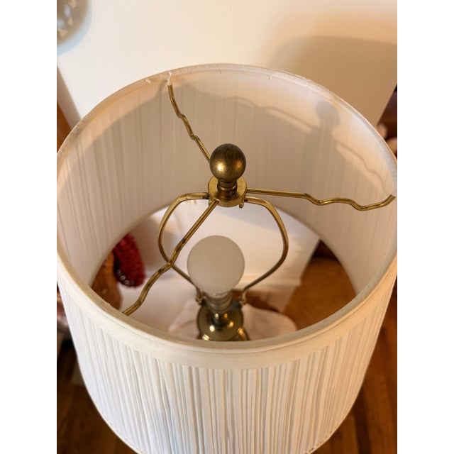 Hollywood Regency Style Brass-Colored Lamp. Raised design of draped fabric. Comes with a pleated shade. Lamp: 31.5" h x 7"...