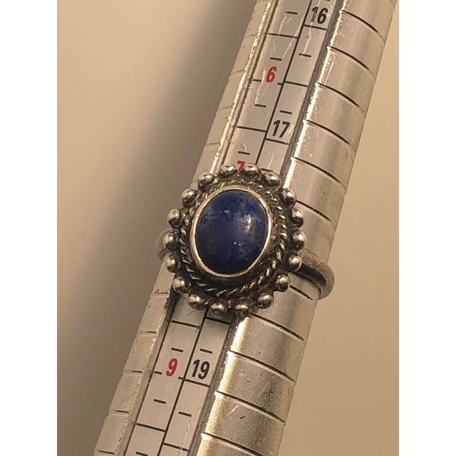 This stunning vintage Navajo Artisan sterling silver ring showcases a beautiful oval-shaped lapis lazuli gemstone embedded...