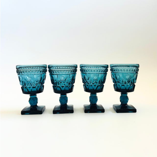 A set of 4 vintage goblets in an ornate design in blue colored glass. Made in the "Park Lane" pattern by Colony Glass, a...