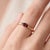 A dainty, modern solitaire featuring a rich red marquise-cut garnet set sideways in an east-west orientation, cradled by a...