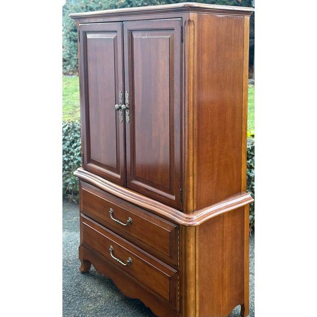 Solid cherry gentleman’s armoire by Drexel Heritage from their French Countryside Collection. Features an upper section...