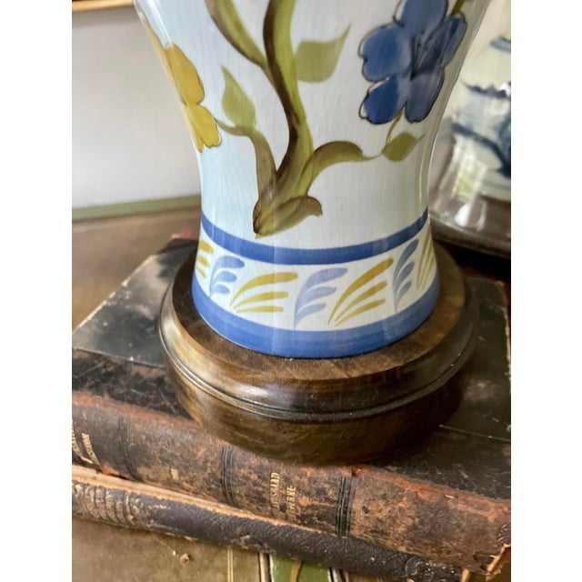 Gorgeous blue pottery lamp, prisoned on a baby blue background with a royal blue floral pattern. Golden flowers mix into...
