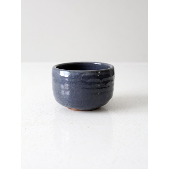This is a vintage studio pottery bowl. Signed by the artist, the small handmade ceramic bowl has a stormy blue glaze.
