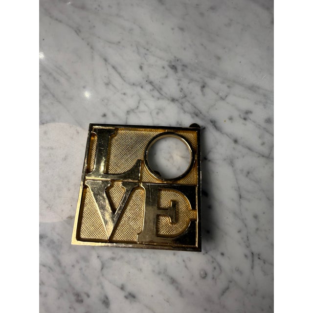 A bold vintage solid brass LOVE sculpture crafted from solid brass with polished raised lettering set against a textured...