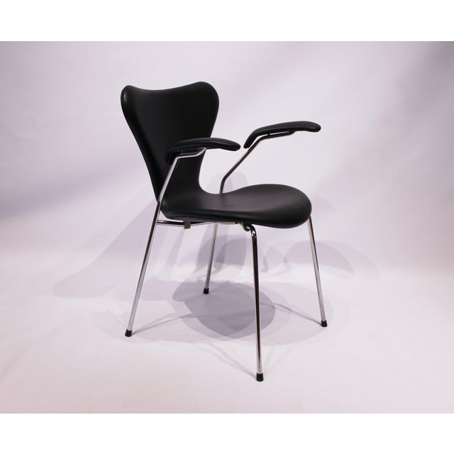 This Seven chair, model 3207, with armrests in black classic leather was designed by Arne Jacobsen in 1955 and...