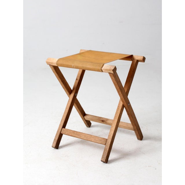Perfect for camping, picnics, or extra seating at home, this vintage American folding camp stool, circa 1940s, is a...