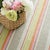 Bright stripes of red, orange, pink, citrus, and sky pop against sage green on this eco-friendly indoor/outdoor rug made...