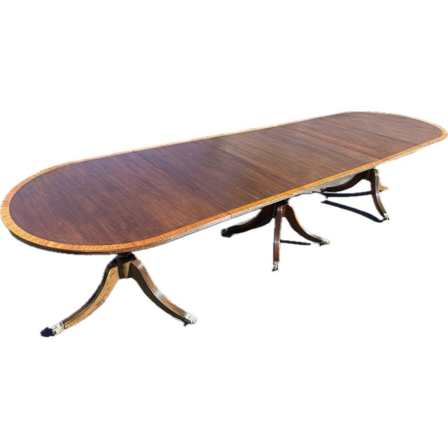 This is an English Regency-style triple-pedestal extension dining table in mahogany and satinwood veneer from the ca....