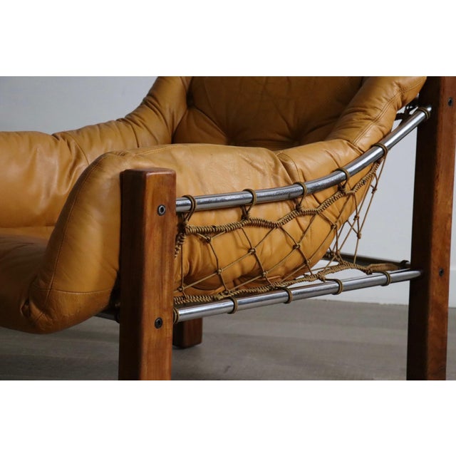 Incredible and rare design by jean gillon, the ‘amazonas’ easy chair with ottoman in cognac leather, wood and metal,...