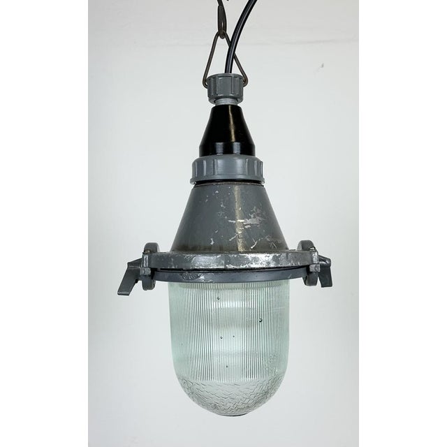 Grey industrial light with massive protective glass bulb. Made in former Soviet Union during the 1960s. It features cast...