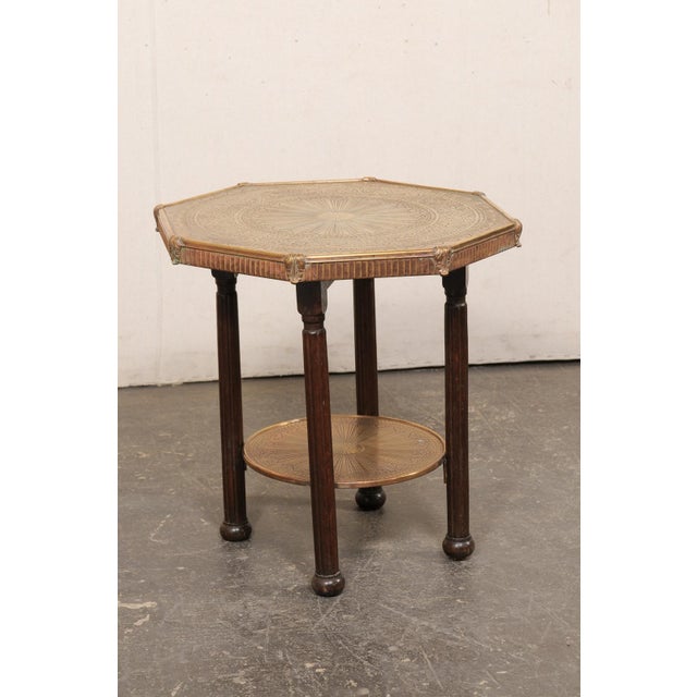 An Italian brass and wood, two-tier accent table from the early 20th century. This antique table from Italy has been...