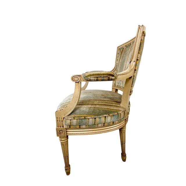 A handsome vintage armchair drawing directly from the neoclassical vocabulary of Louis XVI furniture, pairing a carved...