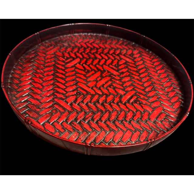 This vintage round serving tray features a dark red woven bamboo texture, commonly known as rantai shikki lacquerware....
