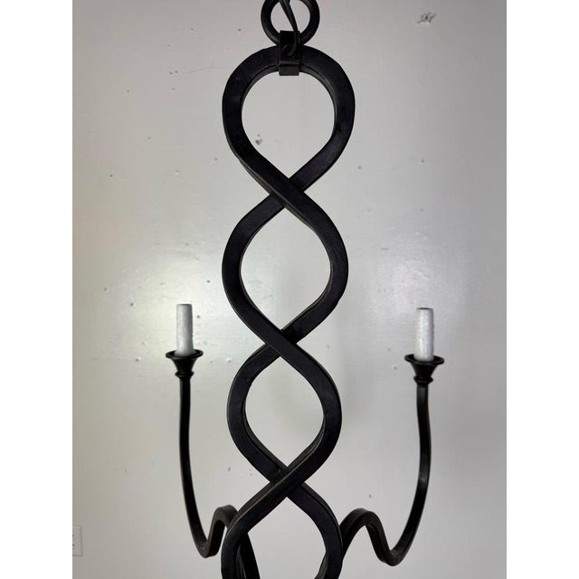 A beautifully hand-forged eight-arm chandelier featuring a dramatic twisted center column and elegantly scrolling arms....