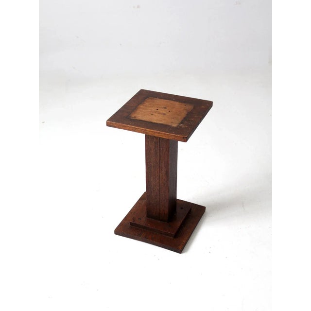 This is an antique Mission style solid wood pedestal table. An ideal plant stand, the side table has a footed base with...