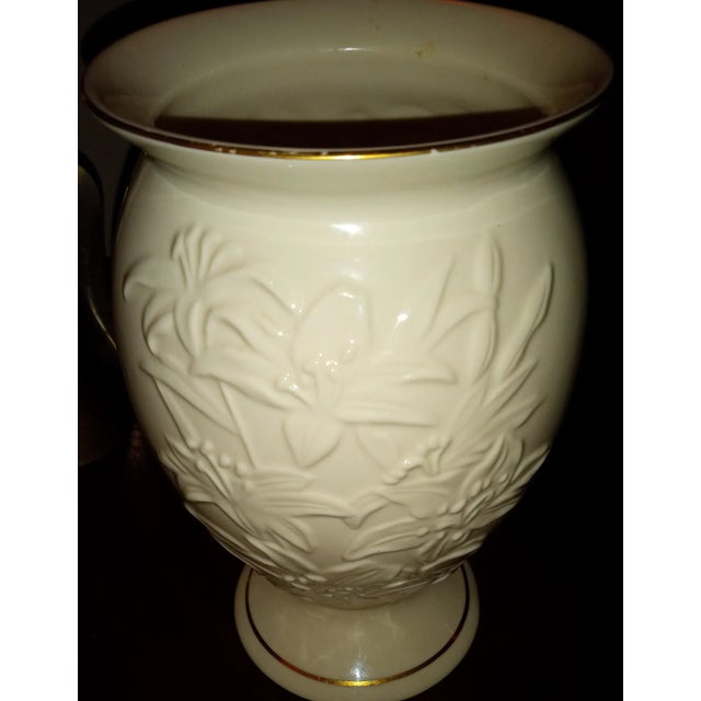 Creamy 8-inch-tall Lenox Vase with 24k gold trim on top rim and bottom. The vase features raised Lilies and is made of...