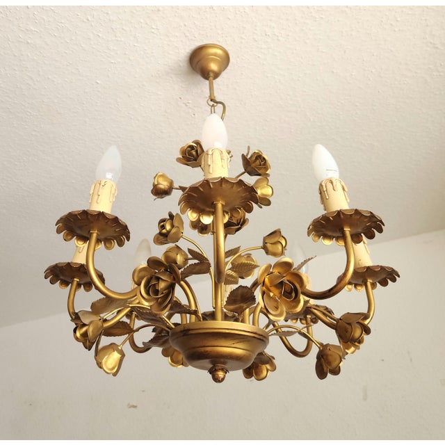 A highly decorative, gold-colored chandelier with rose and leaf embellishments. a stunning vintage chandelier in a floral...