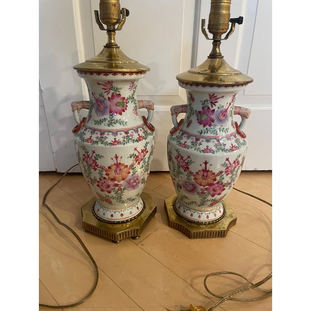Listed is a pair of vintage Chinese export-style Famille Rose porcelain vase mounted lamps, featuring a pink color. These...