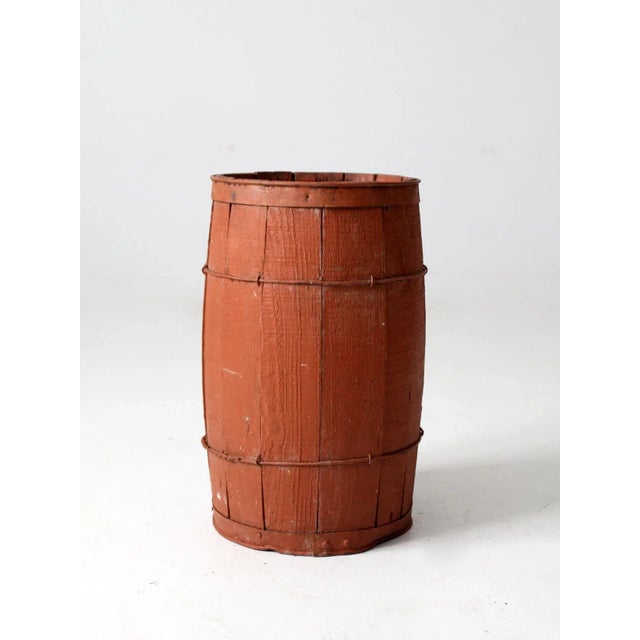 This is an antique primitive painted barrel. The rustic red wooden keg features wood slats and metal banding.