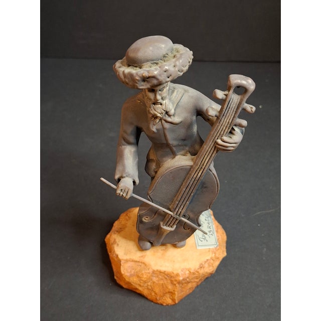 This vintage Israeli Judaica sculpture by renowned artist Fay Avishay depicts a traditional Hasidic musician playing a...