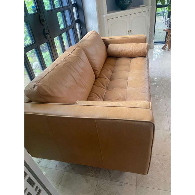 Handsome contemporary sofa upholstered in warm saddle-colored aniline leather, combining clean architectural lines with...