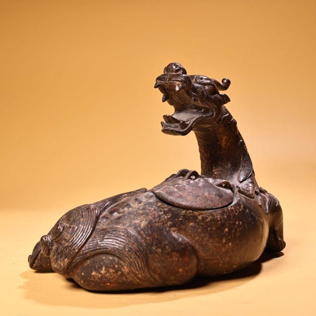 This striking antique gilt bronze sculpture depicts a recumbent mythical beast, possibly a Qilin or a similar guardian...
