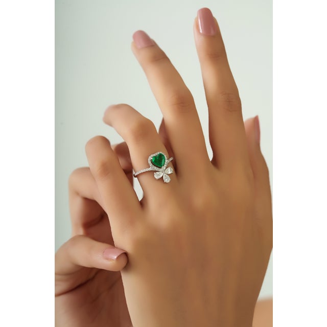 Crafted in 18K white gold, this elegant statement ring features a 0.71 carat heart-shaped emerald measuring approximately...