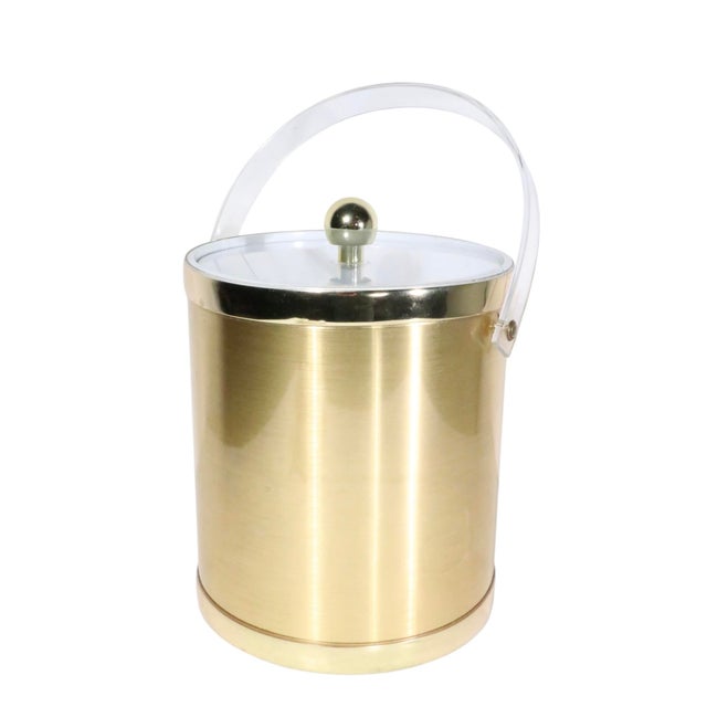 Chic Hollywood Regency style ice bucket having a gold toned exterior with lucite swing handle, original lucite tongs,...