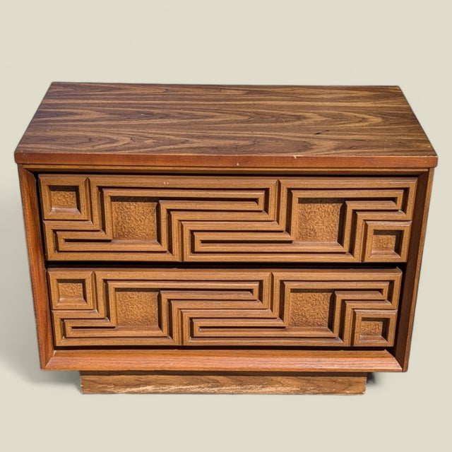 A single vintage nightstand by Bassett Furniture Industries with a warm wood finish, two useful drawers, and a carved...