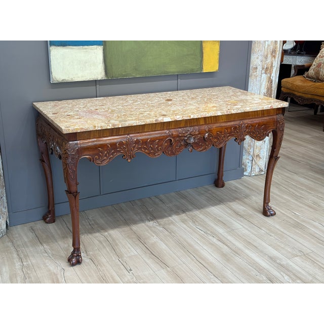 A finely carved Irish console table from the early 19th century with richly detailed apron and cabriole legs ending in paw...