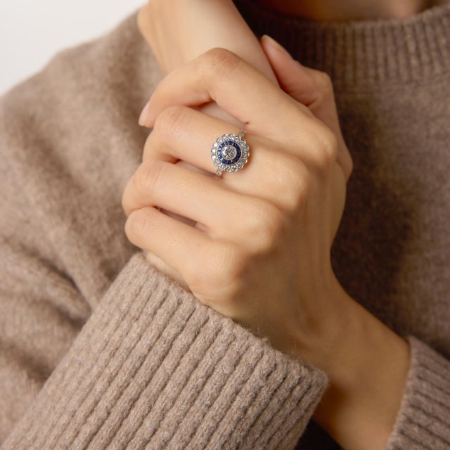 A refined interpretation of classic Deco glamour, this platinum cluster ring centers on a bright 0.41 carat round...